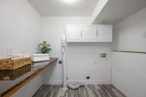 Laundry room with electric dryer hookup, cabinet space, wood finished floors, and washer hookup