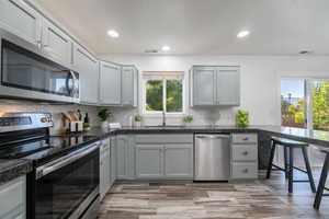 Kitchen with stainless steel appliances, healthy amount of natural light, tasteful backsplash, gray cabinets, and recessed lighting