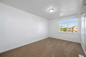 Carpeted spare room featuring baseboards