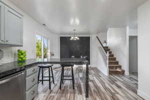 Kitchen featuring stainless steel dishwasher, light wood-style floors, gray cabinets, and decorative backsplash