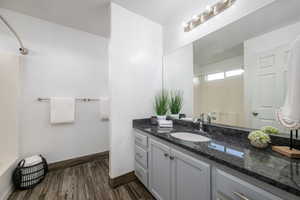 Full bathroom with vanity, wood finished floors, and washtub / shower combination