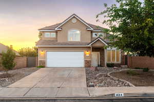 Traditional home featuring stone siding, driveway, an attached garage, stucco siding, and a tiled roof