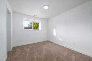 Carpeted spare room featuring baseboards