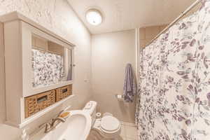 Bathroom featuring tile patterned floors, a shower with curtain, a textured wall, and a textured ceiling
