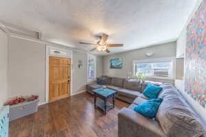 Living room featuring a textured ceiling, wood finished floors, ceiling fan, and cooling unit