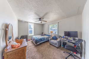 Carpeted bedroom with a textured ceiling and a ceiling fan