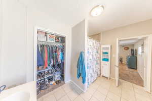 Full bath with tile patterned flooring, curtained shower, and a walk in closet