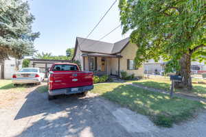 Bungalow-style home with a front yard, stucco siding, and roof with shingles