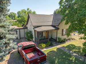 View of front of house featuring stucco siding, covered porch, and a shingled roof
