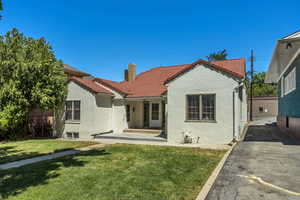 Rear view of house with stucco siding, a tiled roof, a chimney, and a yard