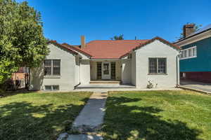 Mediterranean / spanish home with stucco siding, a tile roof, a front yard, and covered porch
