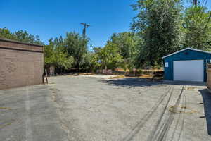 View of yard with an outdoor structure, a garage, and asphalt driveway