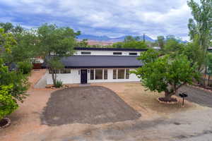 View of front facade with a shingled roof, a mountain view, and driveway