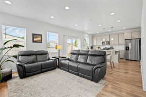 Living room with light wood-style laminate flooring and recessed lighting