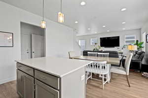 Kitchen featuring gray cabinetry, recessed lighting, light wood-type laminate flooring, a center island, and open floor plan