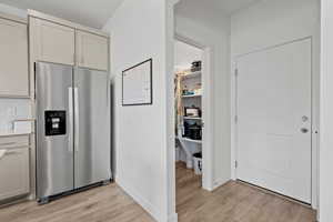 Kitchen featuring stainless steel fridge, light wood-style laminate flooring, light countertops, backsplash, and walk-in pantry
