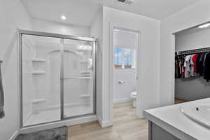 Primary bedroom bathroom featuring a stall shower, vanity, and a walk in closet