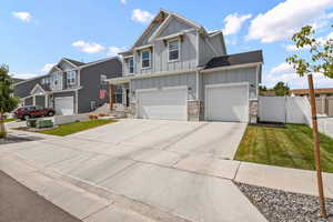 Craftsman-style house with board and batten siding, a gate, concrete driveway, a residential view, and an attached three-car garage