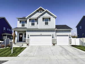 Craftsman-style house featuring board and batten siding, stone siding, concrete driveway, and covered porch