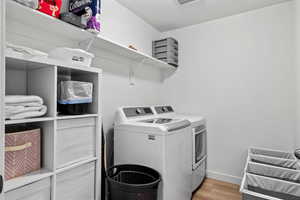Laundry room with washer and dryer and light wood-style laminate flooring