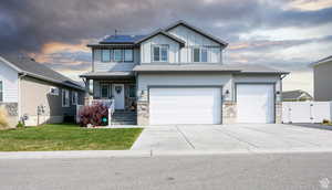 Craftsman house featuring covered porch, roof mounted solar panels, driveway, a garage, and a gate