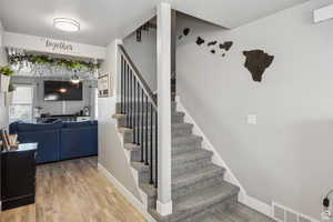 Stairway with wood finished floors and baseboards