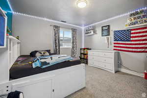 Bedroom featuring light colored carpet and a textured ceiling