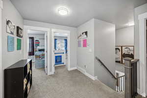 Hall with an upstairs landing, a textured ceiling, and carpet floors