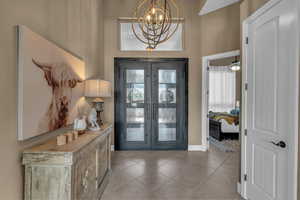 Entryway featuring french doors, light tile patterned flooring, and a chandelier