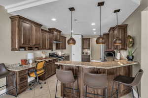 Kitchen featuring built in desk, a peninsula, recessed lighting, gas stove, and dark brown cabinetry