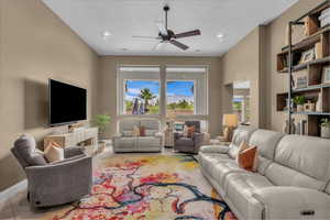 Tiled living room featuring a ceiling fan and baseboards