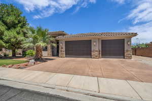 View of front of property with stone siding, stucco siding, a tiled roof, an attached garage, and concrete driveway