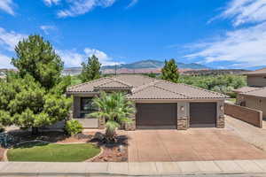 Mediterranean / spanish home with stone siding, stucco siding, a tiled roof, a garage, and concrete driveway