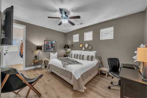 Bedroom with an office area, light wood-style floors, and ceiling fan