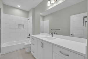 Bathroom with washtub / shower combination, vanity, and light tile patterned floors