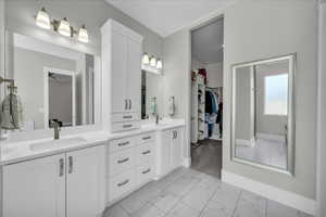 Bathroom with marble look tile flooring, double vanity, and a walk in closet