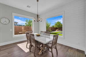 Dining space featuring healthy amount of natural light, a chandelier, and dark wood-style floors