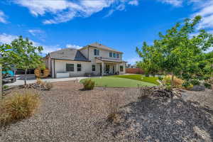 Rear view of house with an area to practice putting, a patio, stucco siding, and a fenced backyard