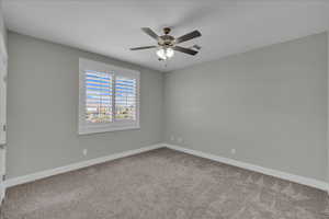 Spare room featuring light colored carpet and a ceiling fan