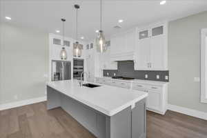 Kitchen with glass insert cabinets, decorative light fixtures, white cabinetry, and recessed lighting