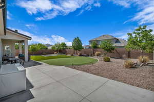 Fenced backyard with a putting area and a patio area