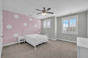 Bedroom featuring light colored carpet, multiple windows, and ceiling fan