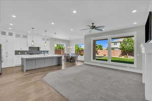 Kitchen featuring white cabinets, plenty of natural light, decorative backsplash, a center island with sink, and recessed lighting