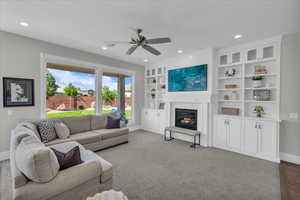 Living room with recessed lighting, a glass covered fireplace, and a ceiling fan