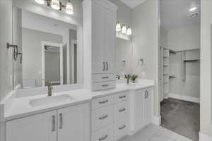 Full bath with double vanity, a walk in closet, and ceiling fan