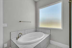 Full bathroom featuring a bath and marble look tiles
