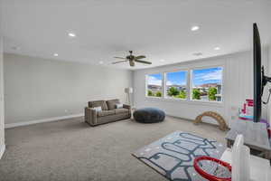 Carpeted living area with a ceiling fan and recessed lighting