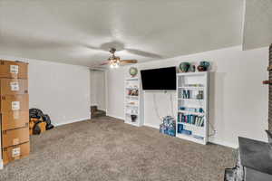 Carpeted living area with a textured ceiling and a ceiling fan