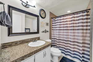 Full bath with vanity, a textured ceiling, a shower with curtain, and decorative backsplash