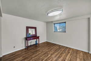 Basement featuring dark wood-type flooring and a textured ceiling